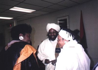 Three people in traditional attire engaged in conversation indoors.